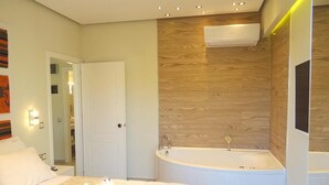 Ein modernes Schlafzimmer mit einem großen Bett, einer eingebauten Badewanne und einer Holzwand.