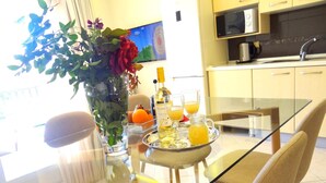 Eine moderne Küche mit einem Glastisch, Stühlen, einer Vase mit Blumen und einem Tablett mit Orangensaft und einer Flasche.