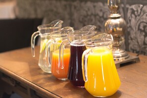 A row of clear glass pitchers with different colored liquids on a wooden surface. - Blue Diamond Boutique Hotel (Pretoria)
