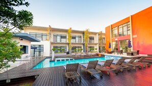 Ein modernes Hotel mit Schwimmbad, Außenbereich und einem mehrstöckigen Gebäude mit Balkonen.