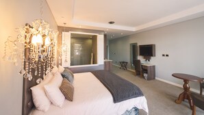 Ein modernes Schlafzimmer mit einem großen Bett, einer Deckenleuchte, einem Schreibtisch und einem Fernseher.