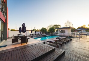 A poolside area with lounge chairs, a table, and umbrellas. - Blue Diamond Boutique Hotel (Pretoria)