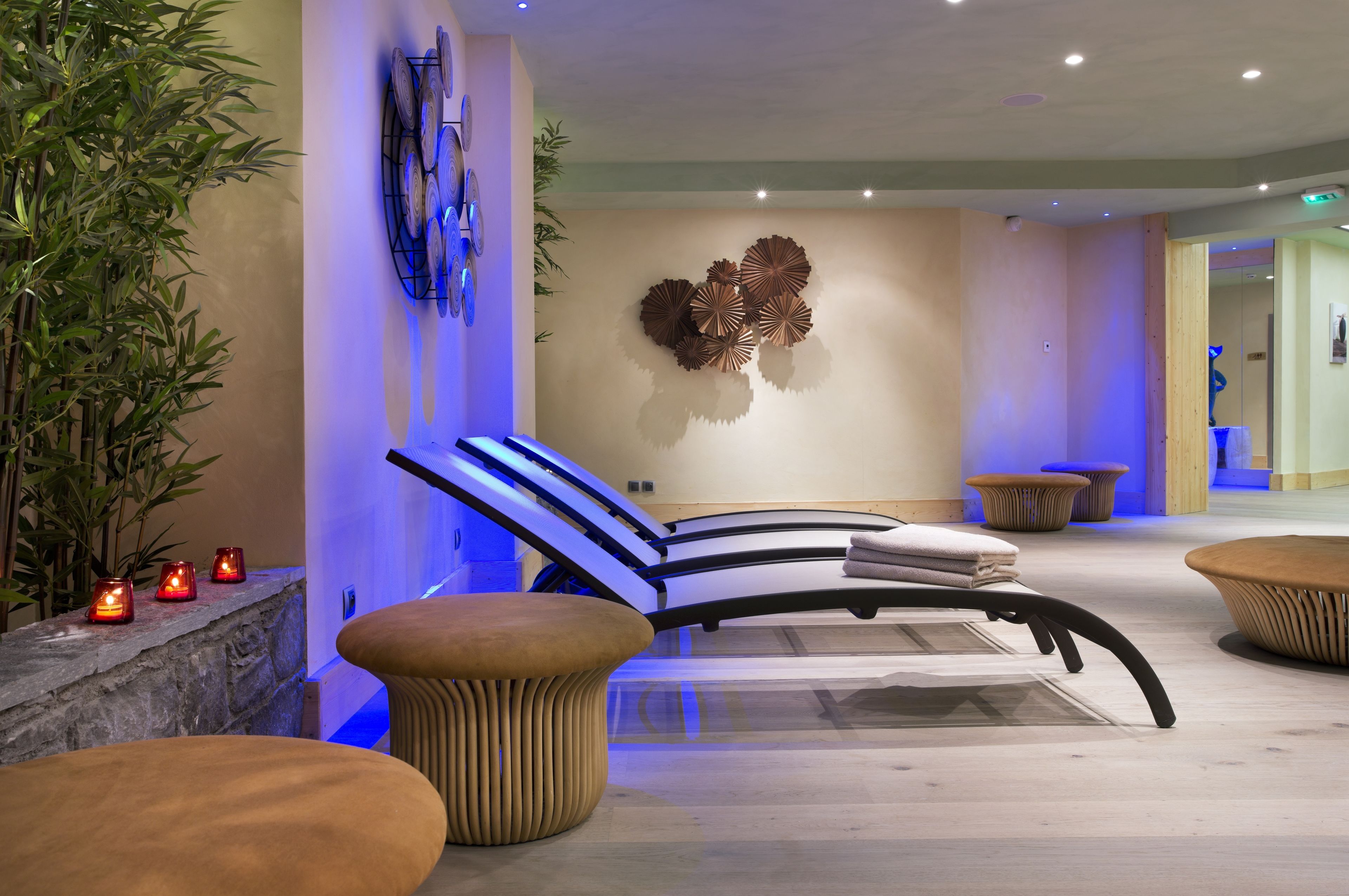 Et moderne spa-område med massagestol, træbænke og en dekorativt ophængt genstand på væggen.