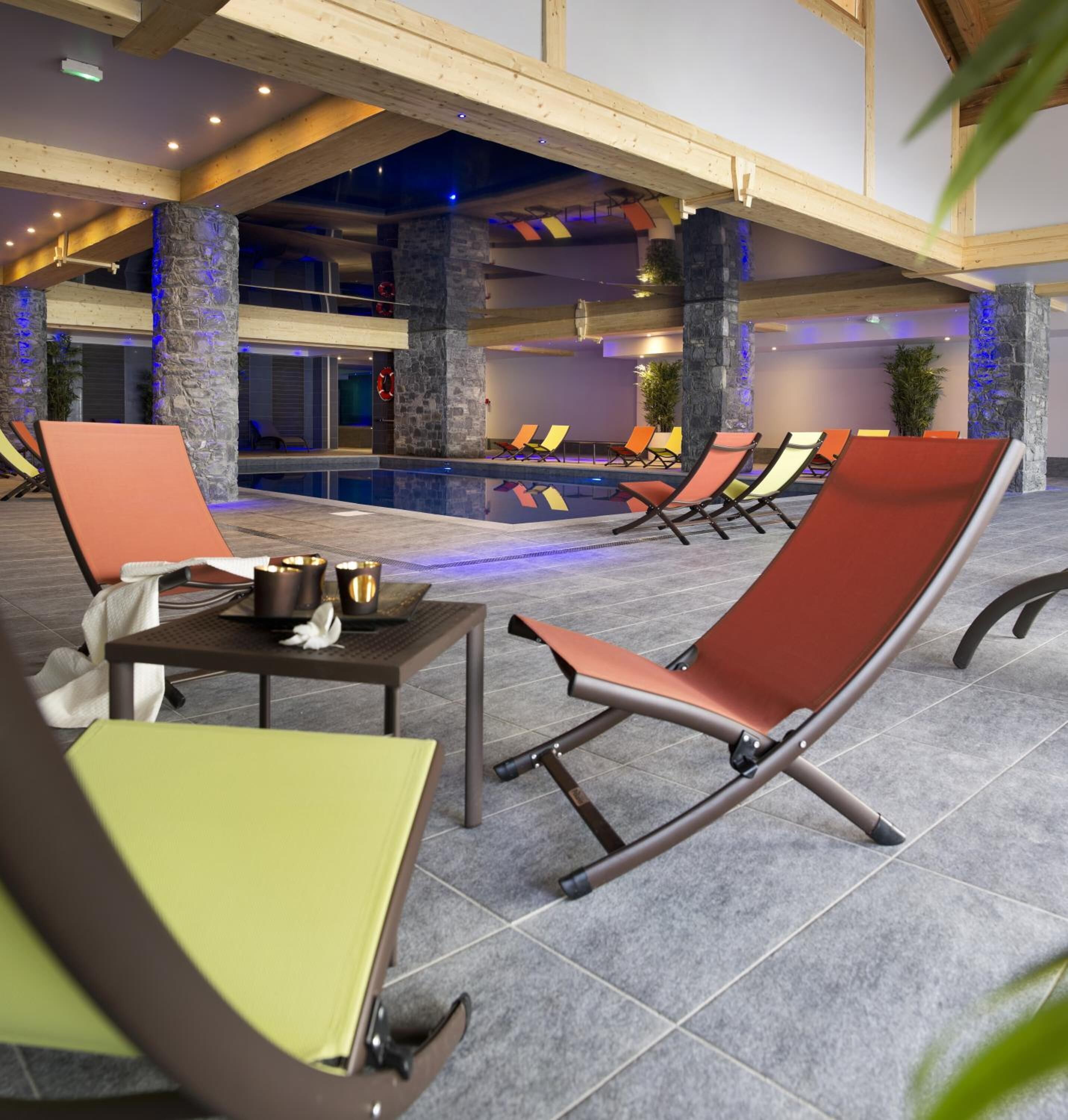 Zona junto a la piscina con sillones de descanso y una mesa con velas.