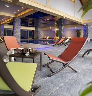 A poolside area with lounge chairs and a table with candles. - CGH  Le Cristal de l’Alpe (Huez)