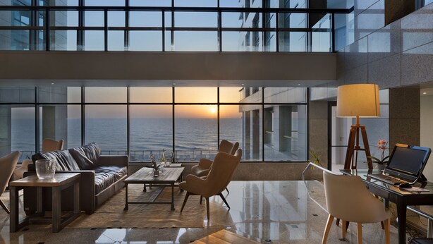 Un espacio habitable amplio con vista al océano, muebles modernos y un ordenador portátil sobre un escritorio.