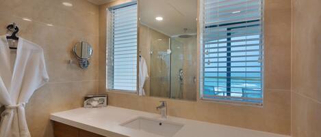 Un baño con un espejo grande, un lavabo y una ducha.