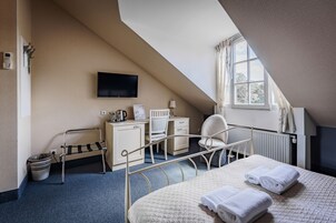 Una habitación de hotel con cama, escritorio, silla, televisor y ventana.