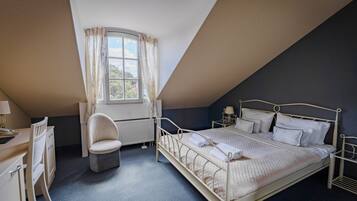 A bedroom with a bed, a desk, a chair, a window, and a radiator.