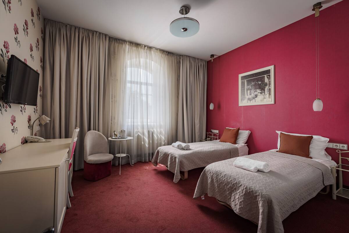 Een hotelkamer met twee bedden, een bureau, een stoel, een tafeltje en een televisie.