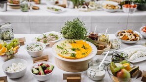 A buffet table with various food items and condiments, including fruits, cheeses, and salads.
