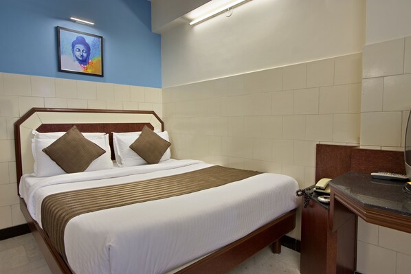A hotel room with a bed, a desk, and a phone.