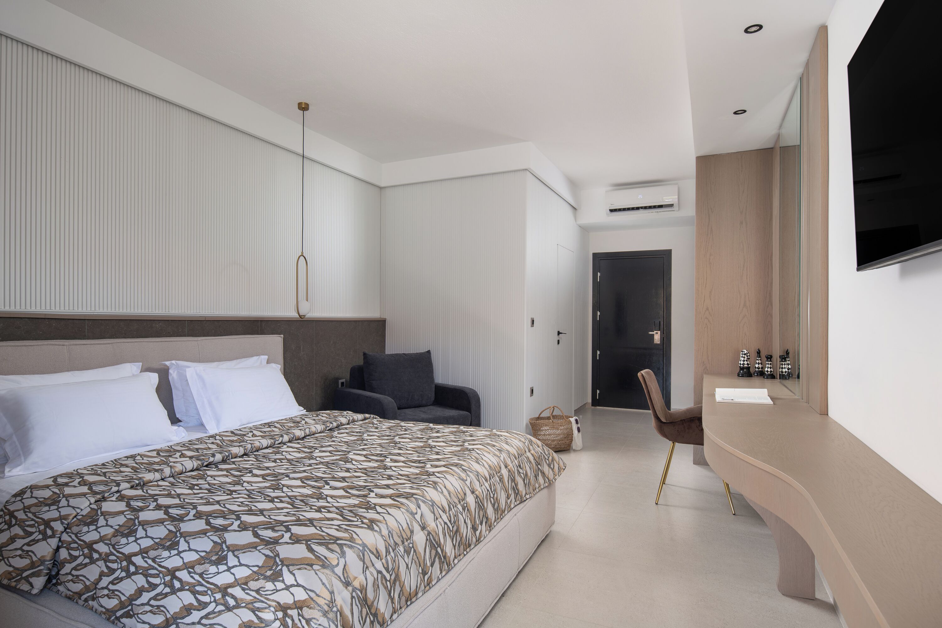 A modern hotel room with a large bed, a desk, and a TV.