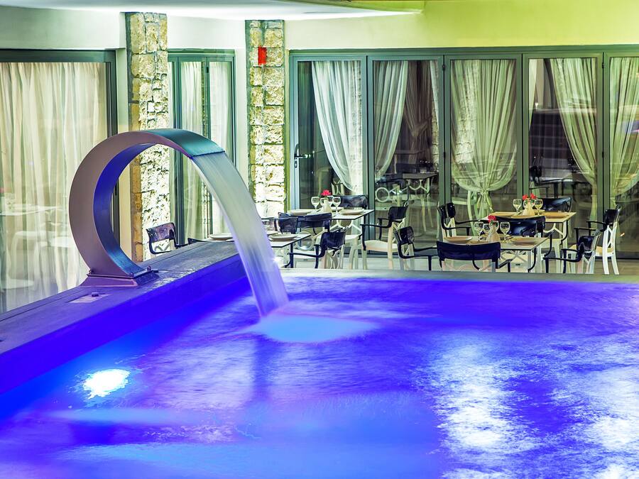 Una piscina al aire libre, una piscina con cascada, tumbonas