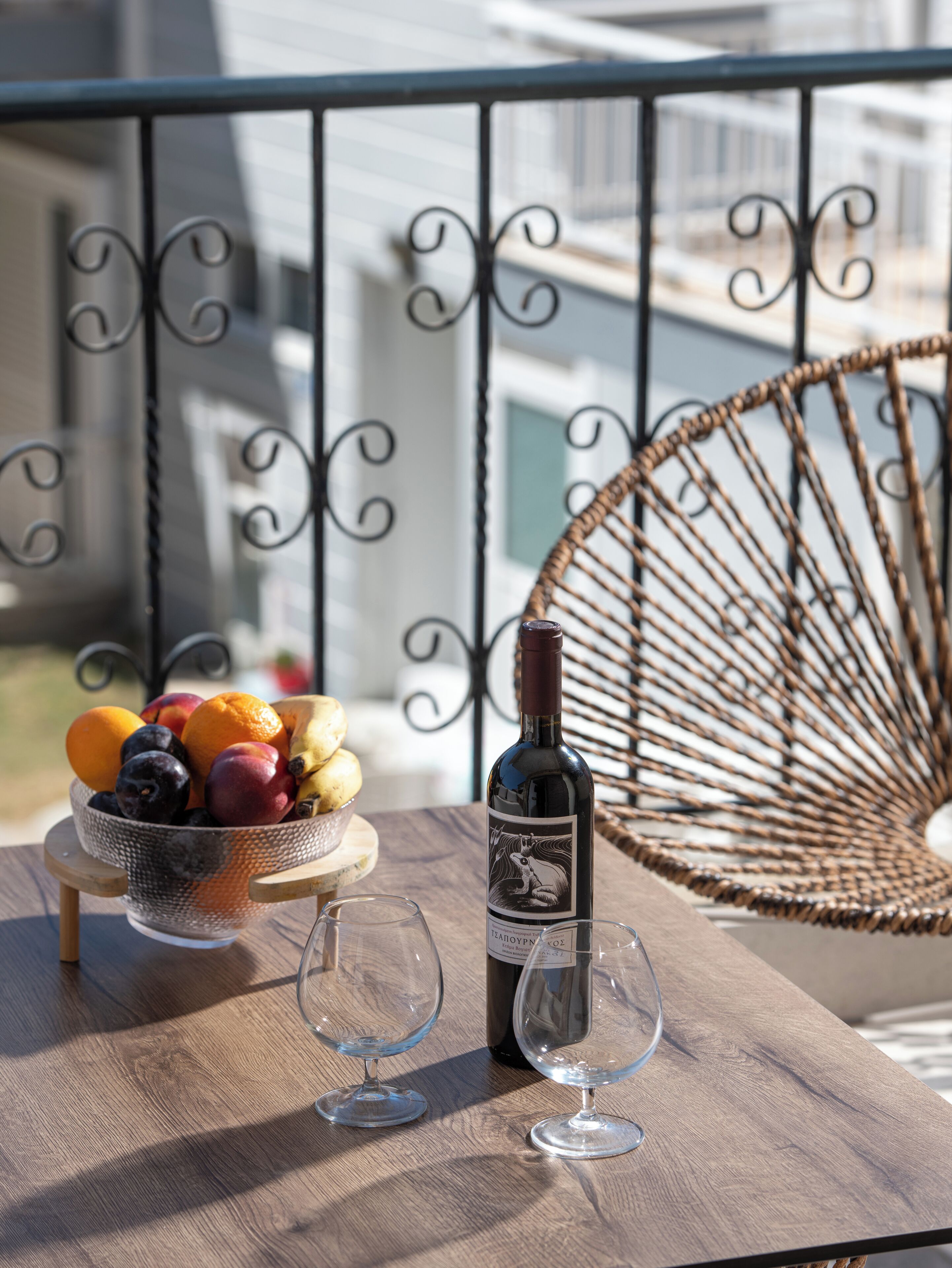 Uma mesa com uma garrafa de vinho, duas taças de vinho e uma cesta de frutas.