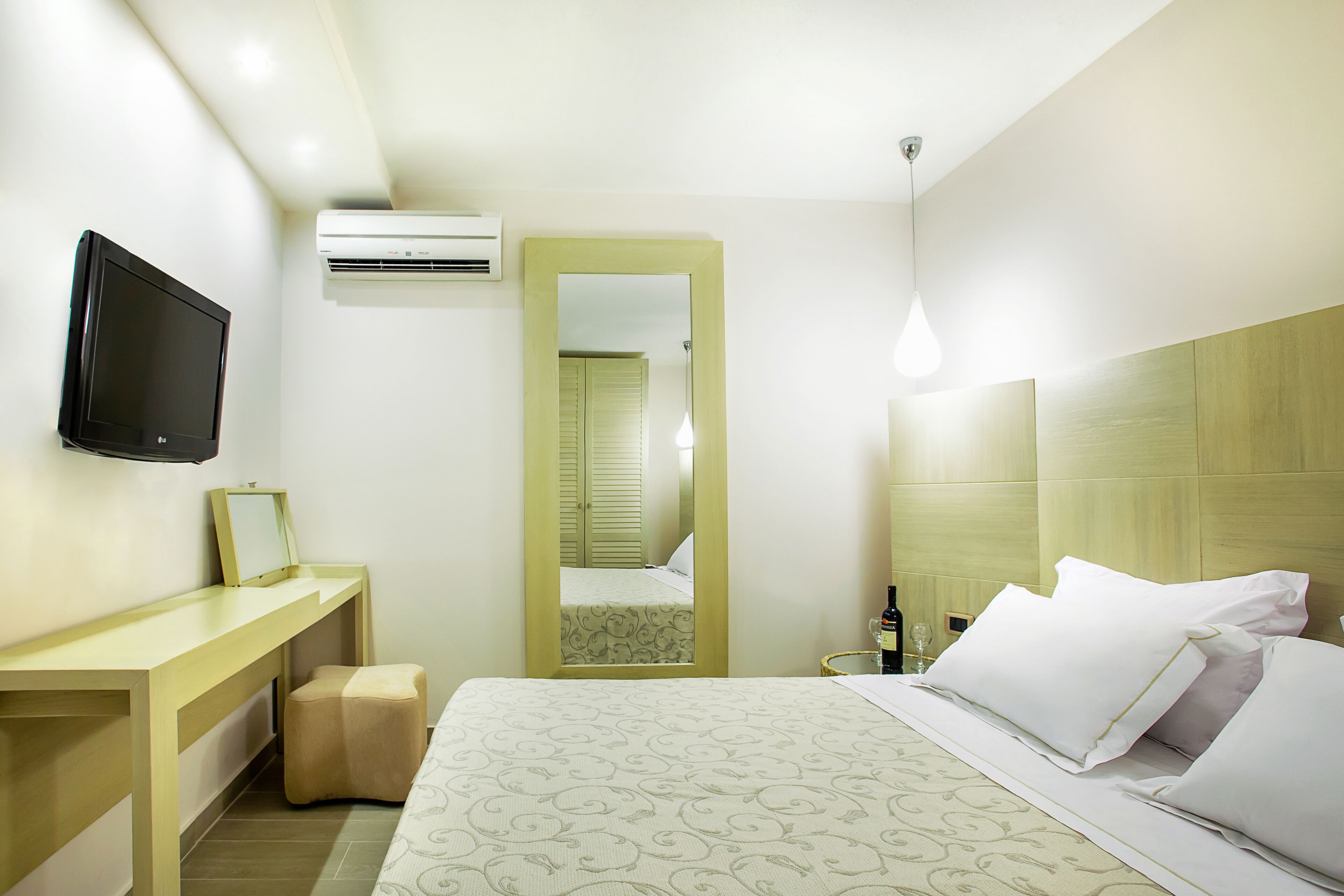 Una habitación de hotel con una cama, un escritorio, un televisor y un aire acondicionado.