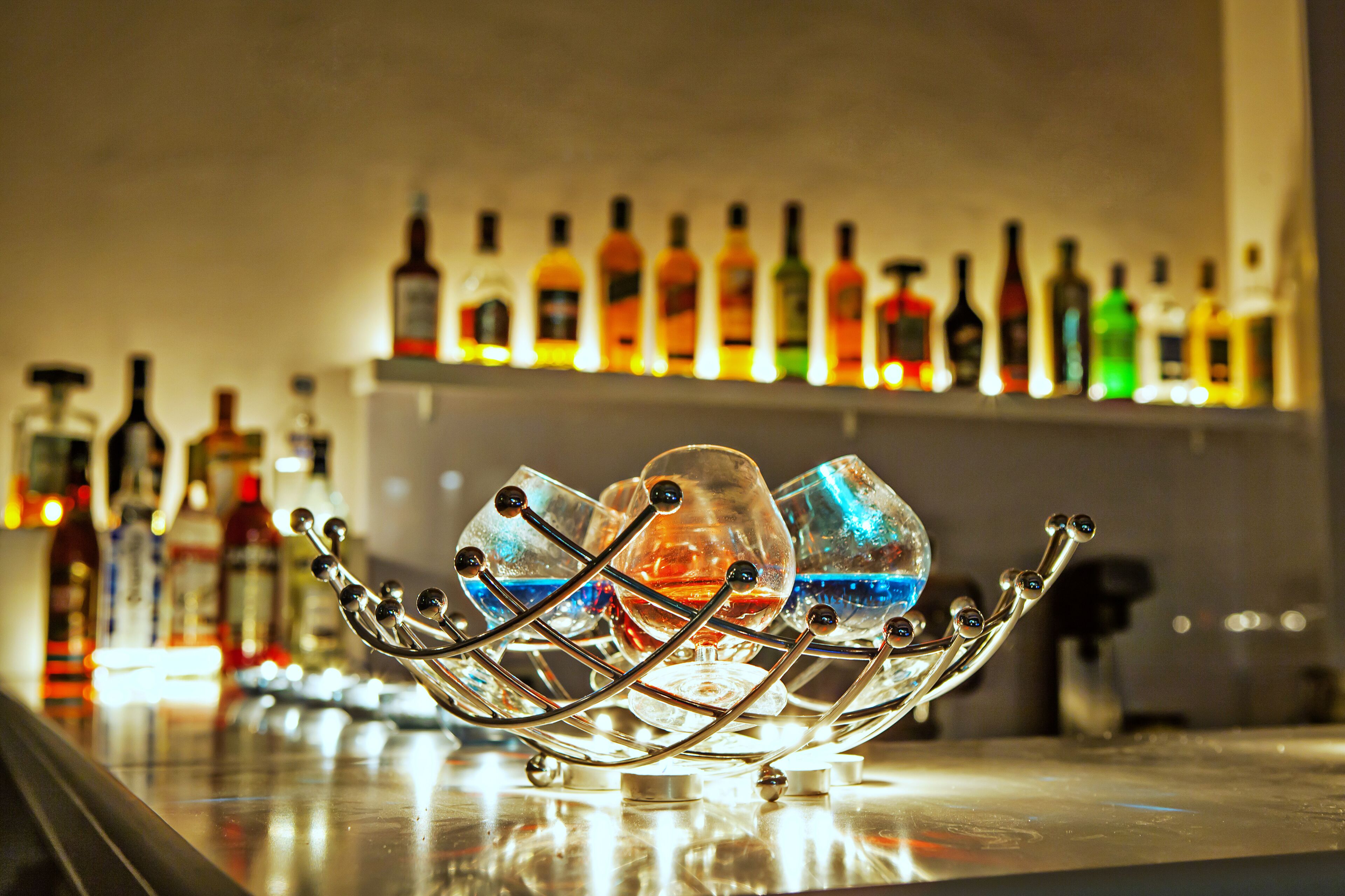 A bar setting with a decorative glass holder and a row of bottles in the background.
