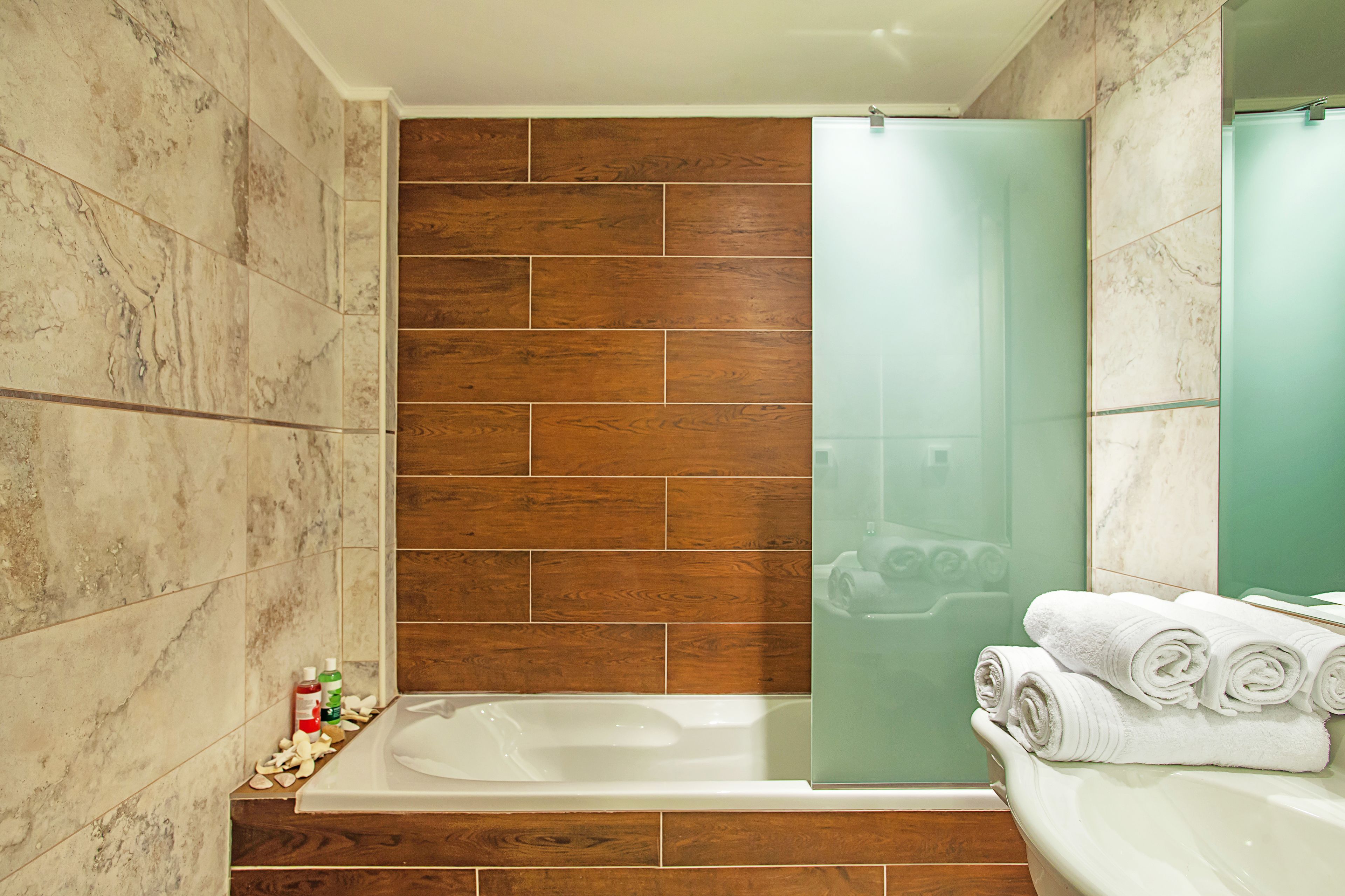 A bathroom with a bathtub, a glass shower enclosure, and a sink with towels.