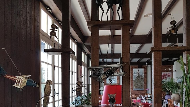 Un interior rústico con vigas de madera, una escultura colgante y una variedad de objetos decorativos.