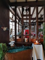 A rustic interior with wooden beams, a hanging sculpture, and a variety of decorative items.