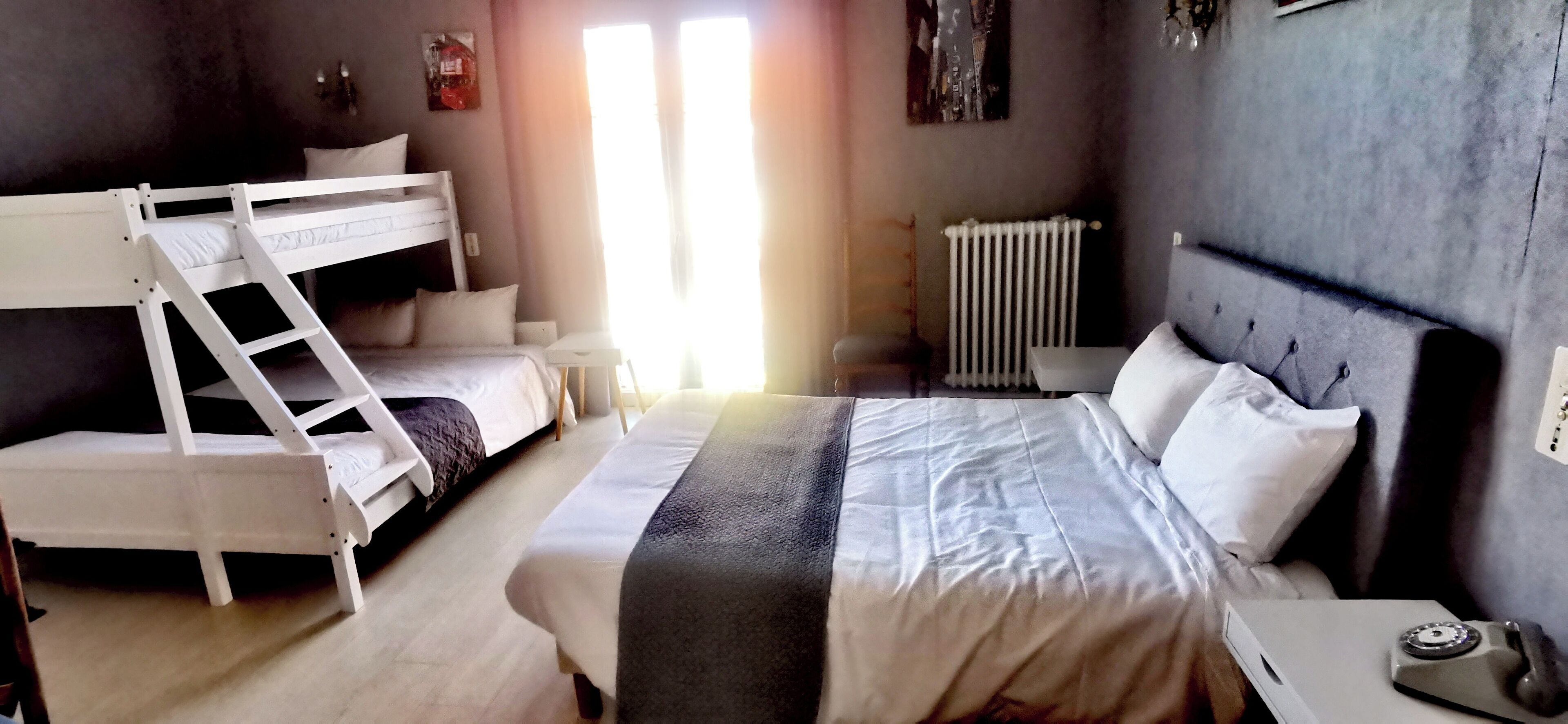 A room with bunk beds, a bedside table with a telephone, and a radiator.