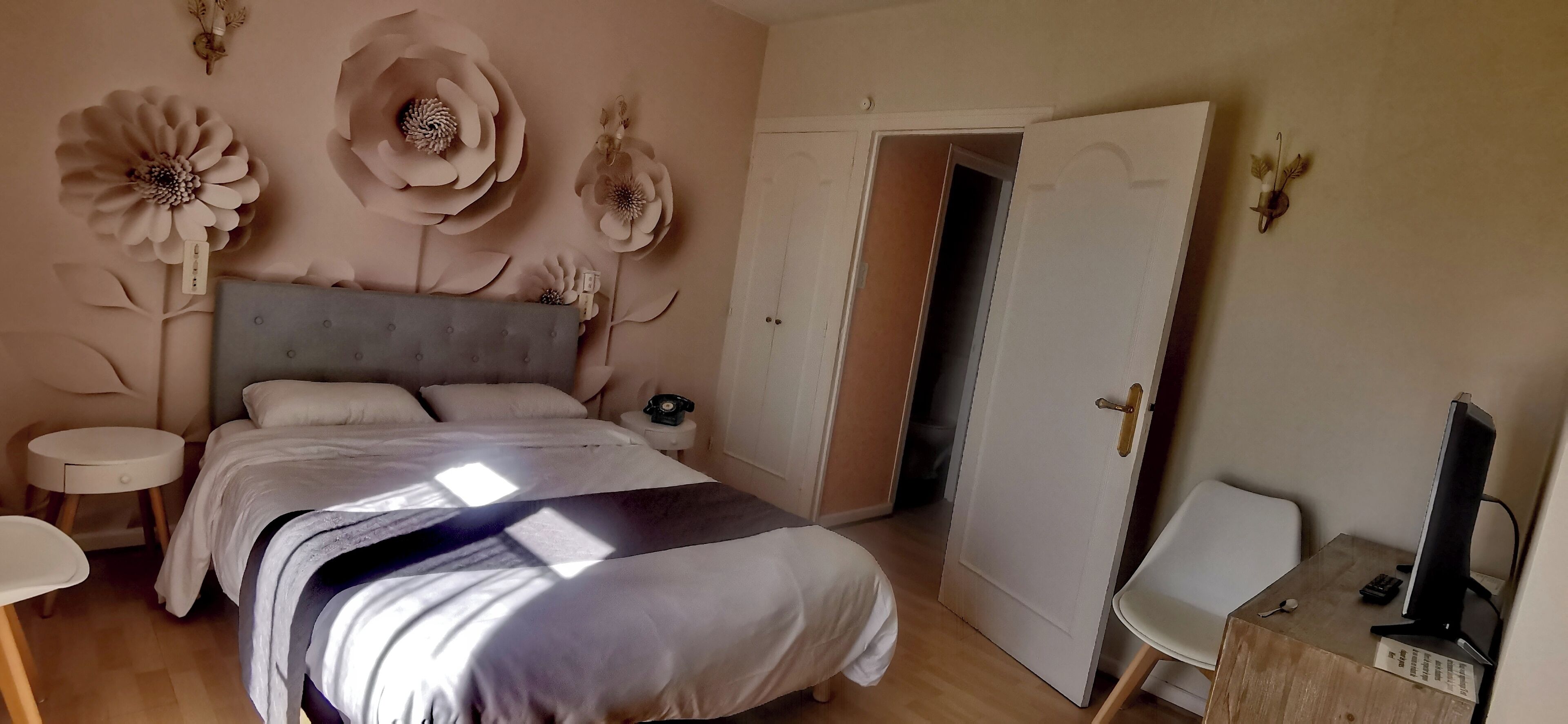 A bedroom with a bed, a bedside table, a chair, and a desk with a computer.
