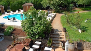 Un jardín trasero con piscina, mobiliario de patio y zona ajardinada.