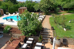 A backyard with a swimming pool, patio furniture, and a garden area.