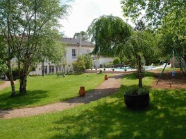 A garden with a pathway, a swing set, and a building in the background.