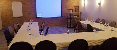 A conference room with a long table, chairs, a projector screen, and a whiteboard.