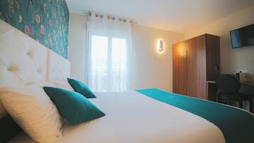 A hotel room with a large bed, a desk, and a wardrobe.