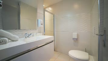 Un baño moderno con un lavamanos, espejo y retrete blancos.