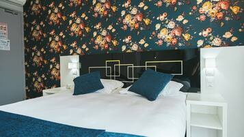 A hotel room with a large bed, two bedside tables, and a floral wallpaper.