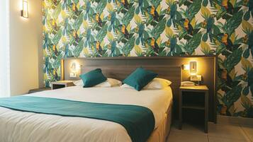 A hotel room with a large bed, two nightstands, and a wall with a tropical leaf and bird pattern.