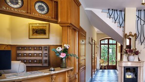 A reception area with a wooden desk, a clock, a framed picture, a vase with flowers, and a checkered floor.