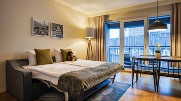 Habitación de hotel moderna con cama, mesita de noche y balcón con vistas.