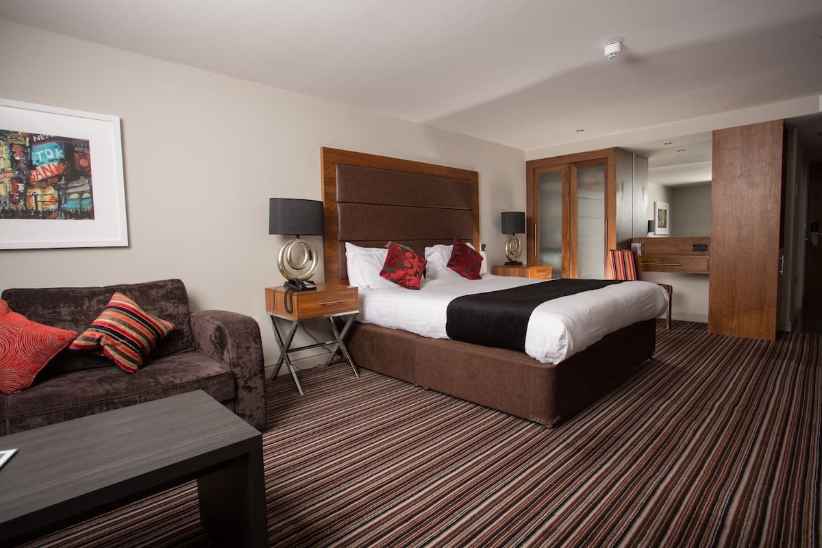 Een hotelkamer met een groot bed, een bank, een bureau en een spiegel.