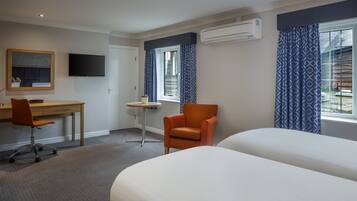 Hotellihuone, jossa on kaksi sänkyä, työpöytä, tuoli, televisio ja ilmastointilaite.