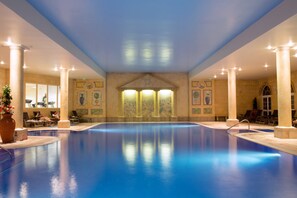 Una piscina interior con columnas, una fuente y obras de arte en las paredes.