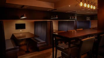 L'intérieur d'un restaurant avec des banquettes, une table en bois et des luminaires suspendus.