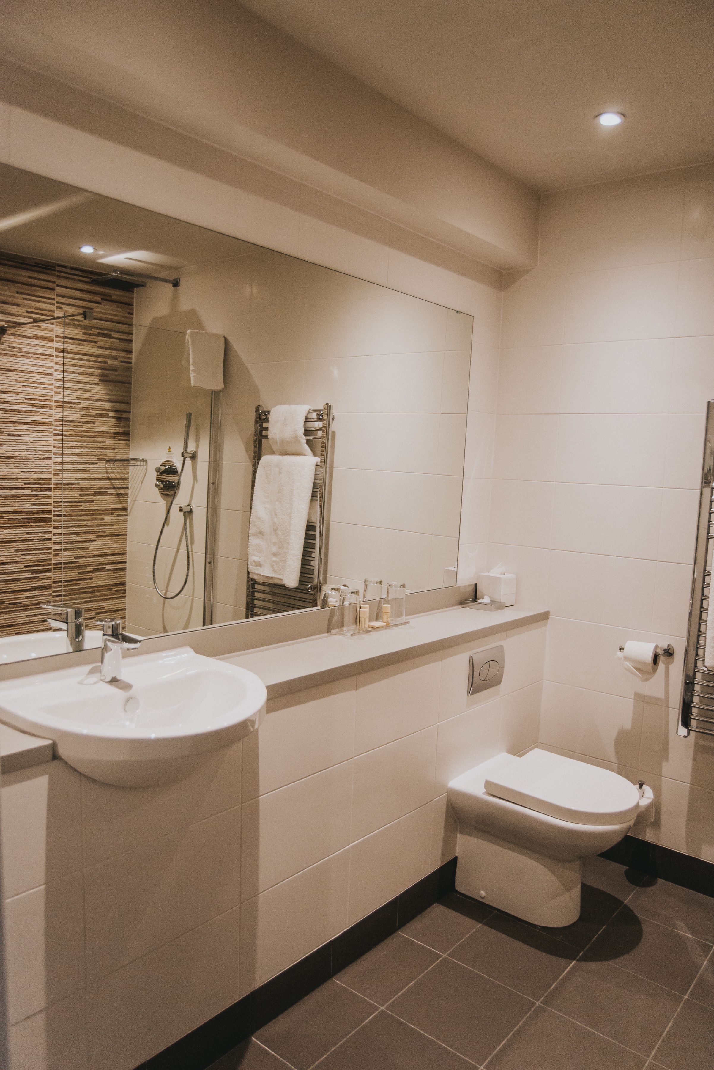 A modern bathroom with a sink, mirror, toilet, and shower.