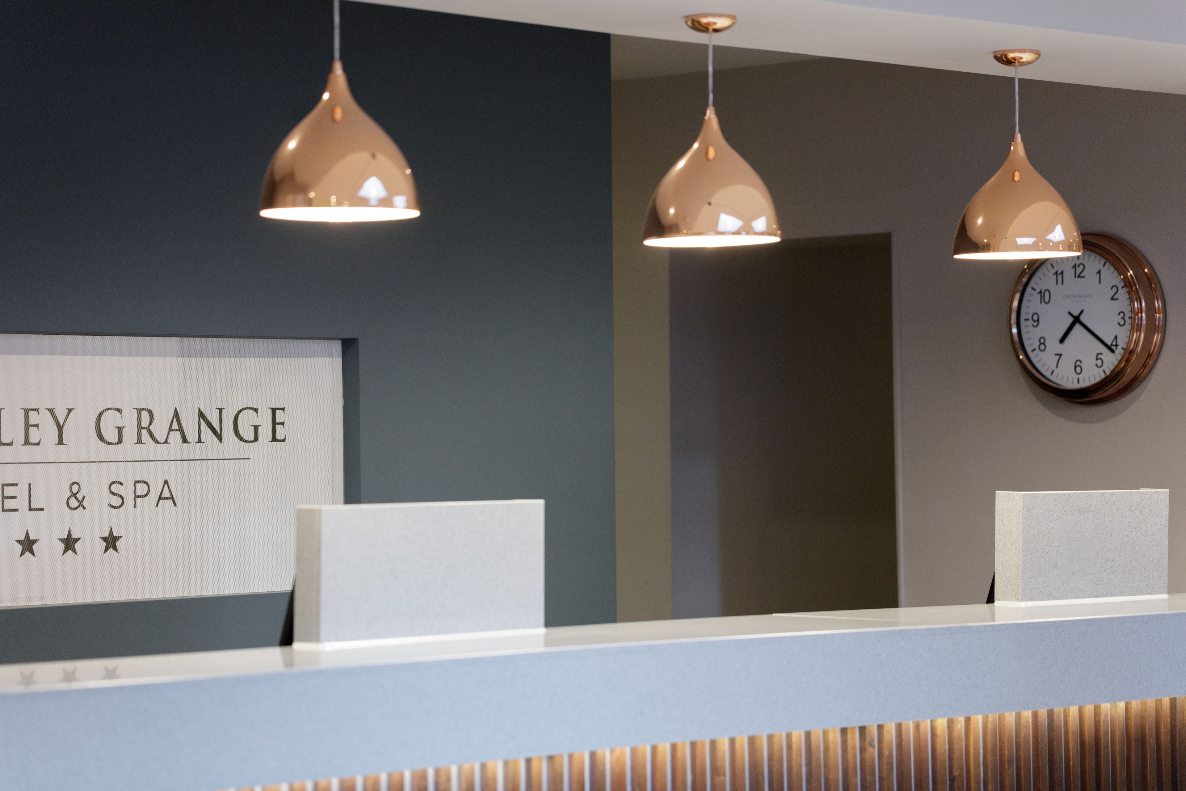 A reception desk with a sign reading "LEY GRANGE HOTEL & SPA" and a wall clock.