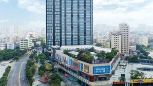 Un hotel de gran altura con un llamativo letrero de Hilton Garden Inn, rodeado de edificios urbanos y una tienda Walmart.