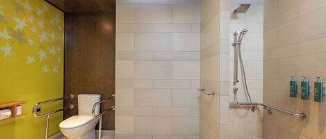 A bathroom with a toilet, a shower with grab bars, and a green wall with leaf patterns.