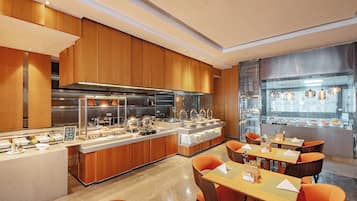 Een modern restaurant met houten lambrisering, een buffet en oranje stoelen.