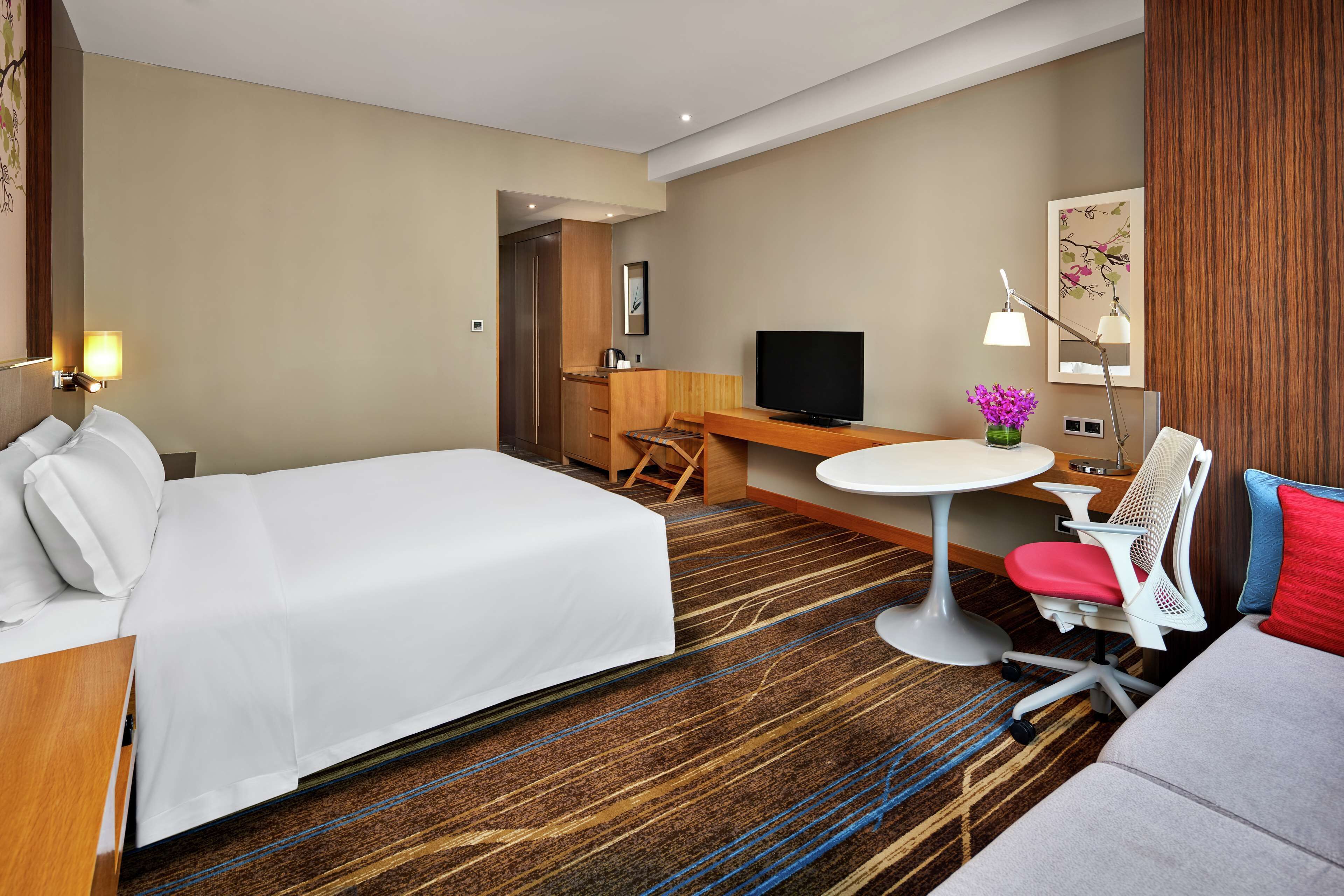 A hotel room with a bed, a desk, a TV, a chair, and a small table.