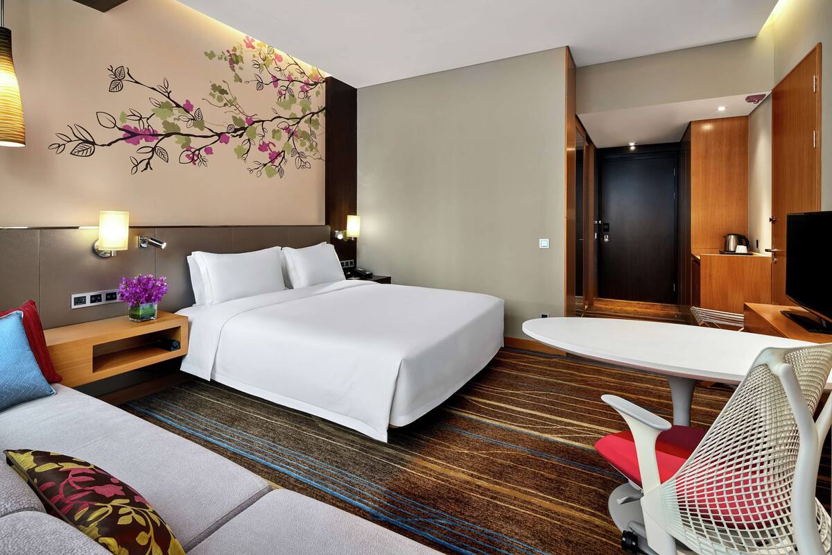Una habitación de hotel con cama, sofá, escritorio y televisor.