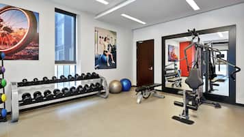 A gym with exercise equipment, dumbbells, and exercise balls.