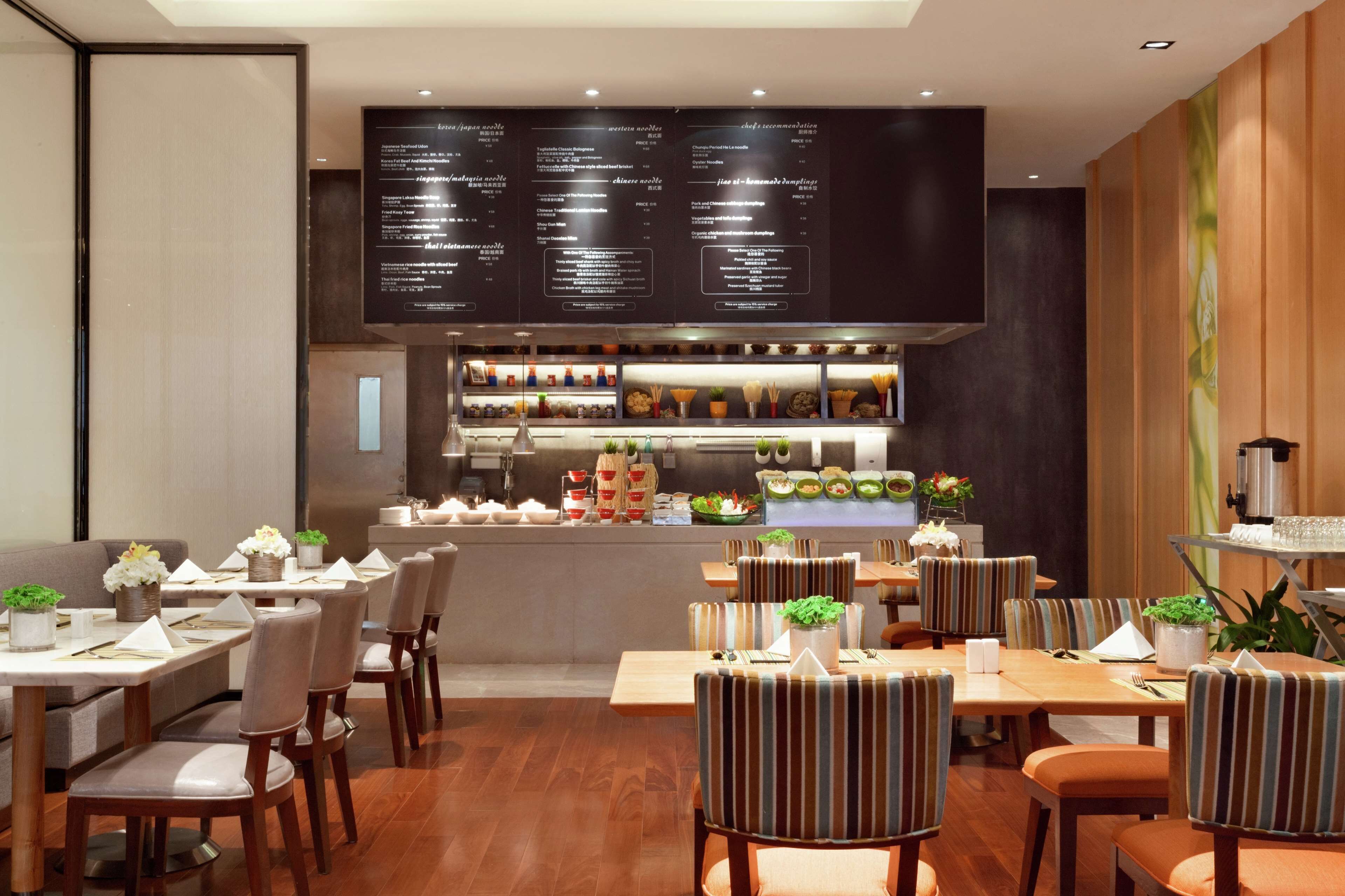 A restaurant with a dark menu board, wooden tables, and striped chairs.