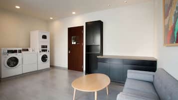 A modern living room with a grey sofa, a wooden coffee table, and a built-in kitchen area with dark cabinetry.